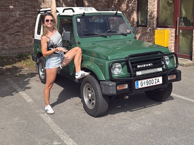 Vanessa celebrating next to the green Suzuki Samurai after its engine overhaul in Zagreb